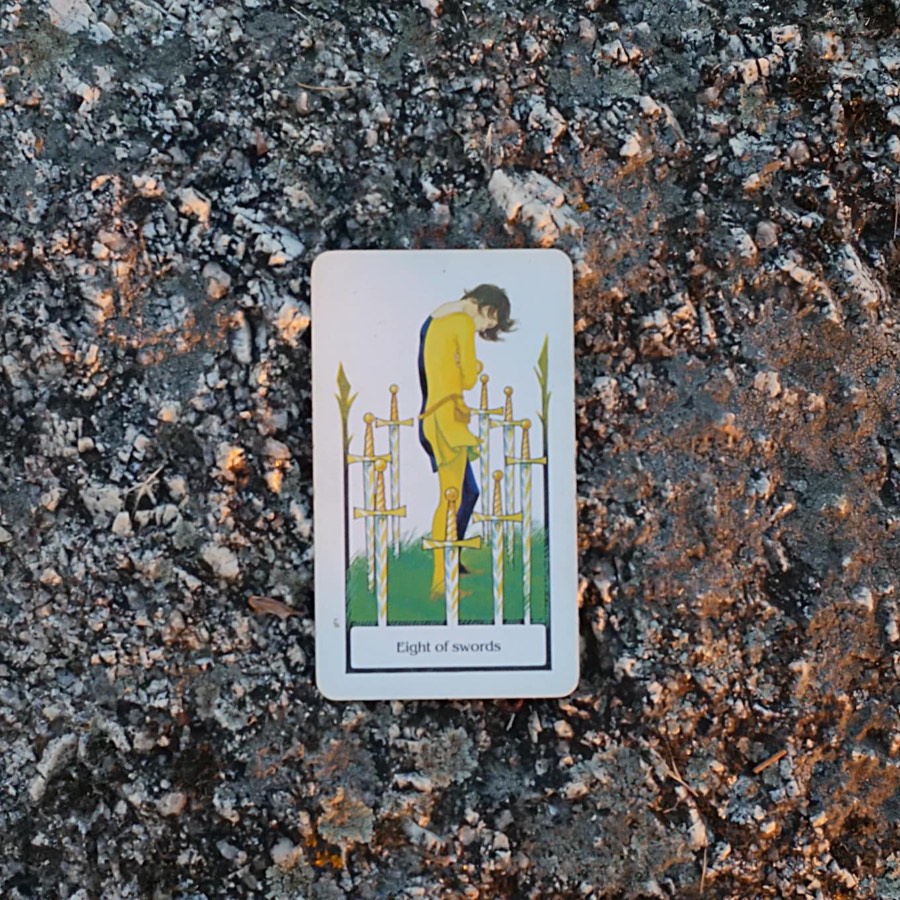 The Eight of Swords tarot card photographed outdoors