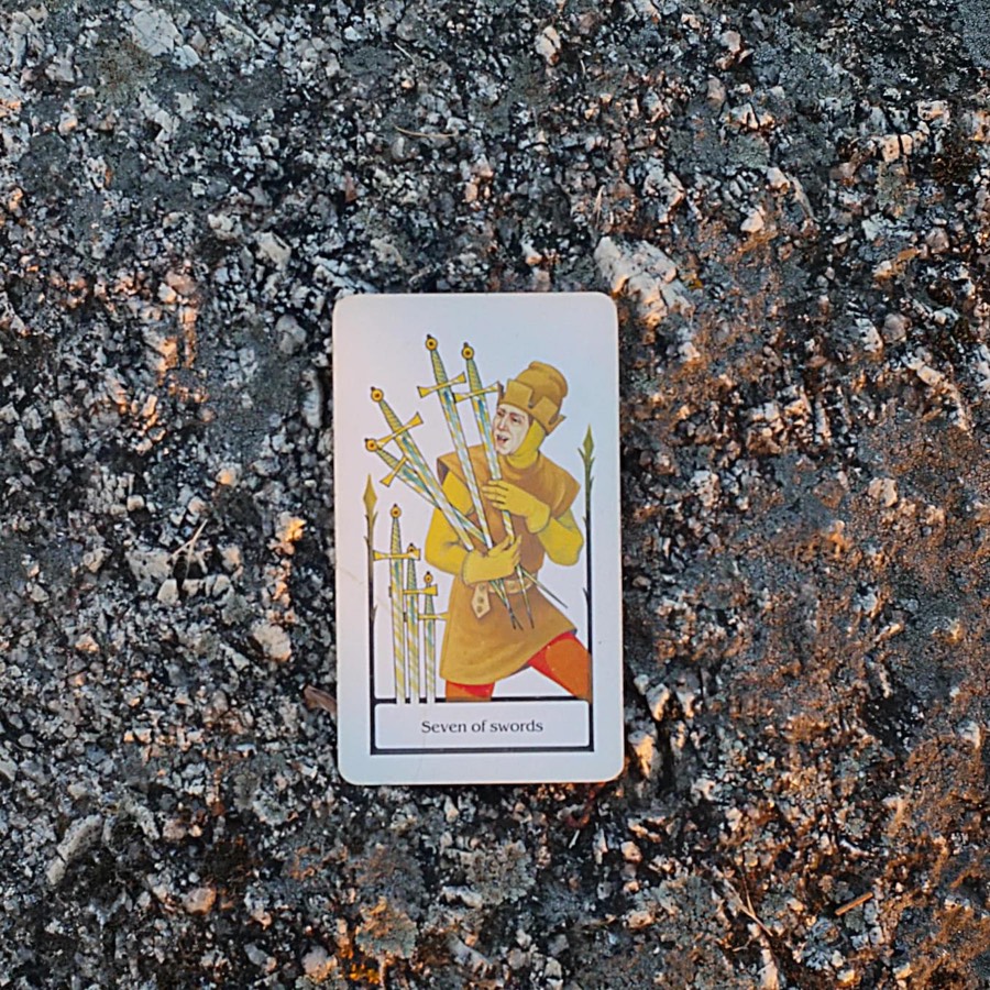 The Seven of Swords tarot card photographed outdoors
