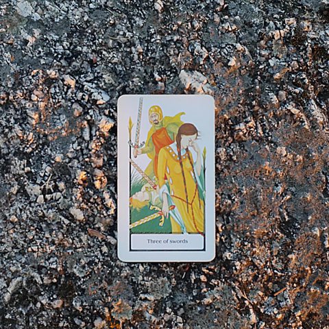 Three of Swords tarot card, photographed outdoors