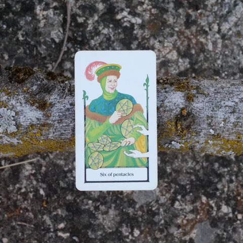 Six of Pentacles tarot card, photographed outdoors